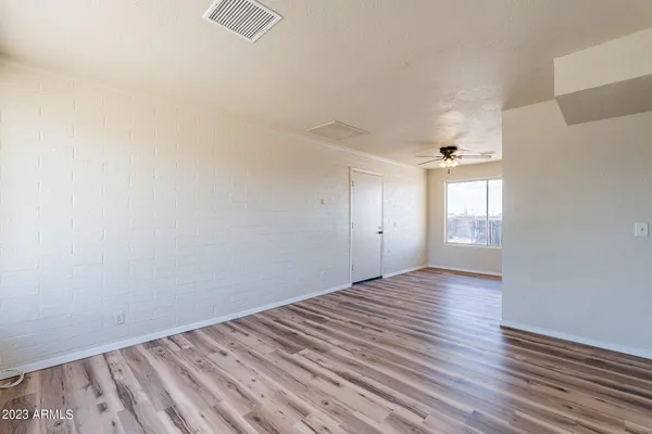 a view of an empty room with a window and wooden floor