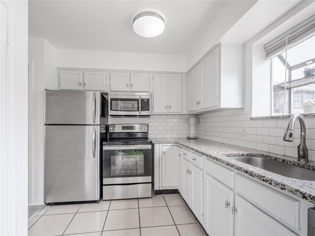 4748 Old Bent Tree Lane, Unit 201 Dallas, TX 75287 - Photo 12 of 17 Kitchen with appliances with stainless steel finishes, light stone countertops, decorative backsplash, light tile patterned flooring, and white cabinets