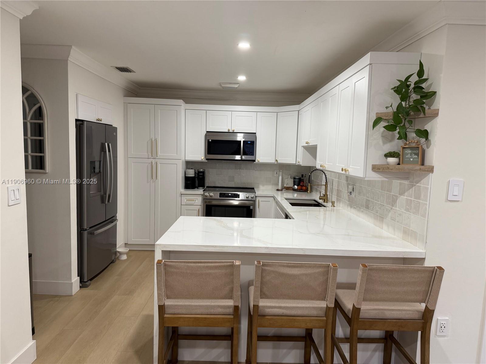 20912 Southwest 125th Avenue Road Miami, FL 33177 - Photo 7 of 25 a kitchen with kitchen island a refrigerator stove and microwave