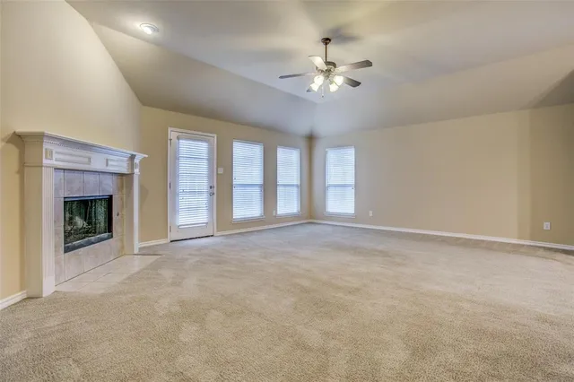 a view of an empty room with chandelier fan and fire place