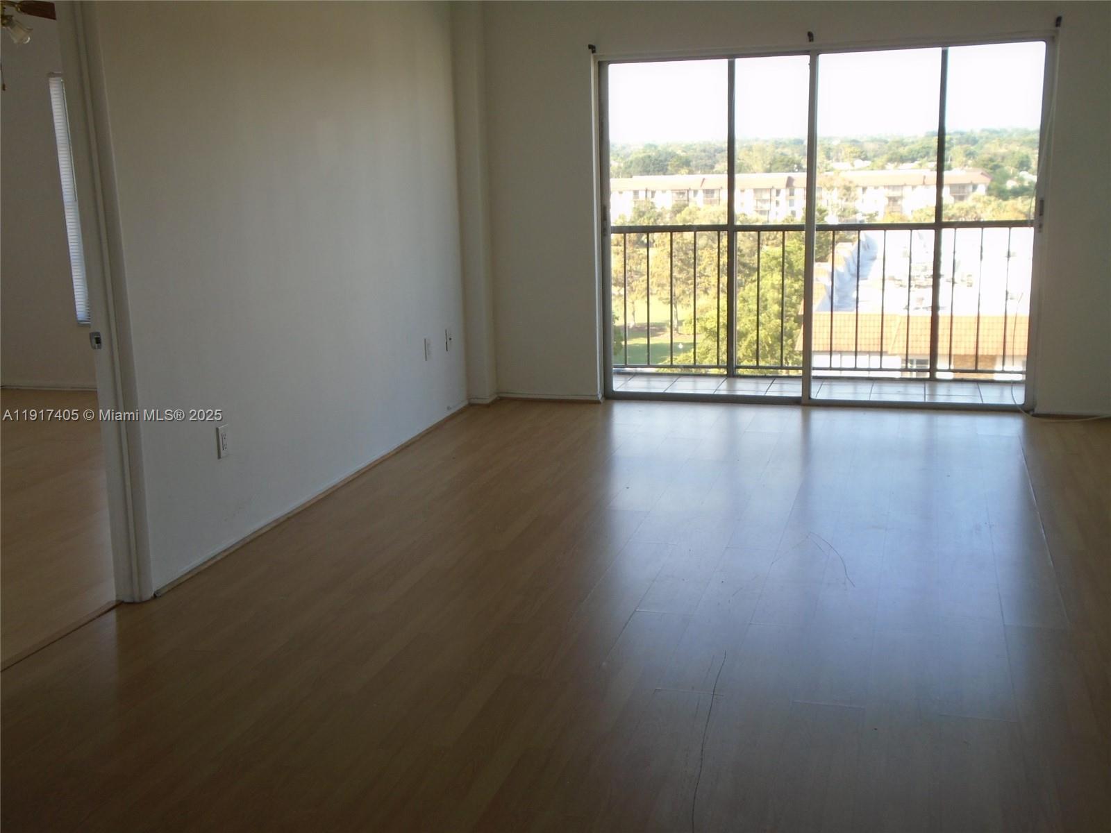 4174 Inverrary Drive, Unit 1003 Lauderhill, FL 33319 - Photo 4 of 28 wooden floor in an empty room with a window