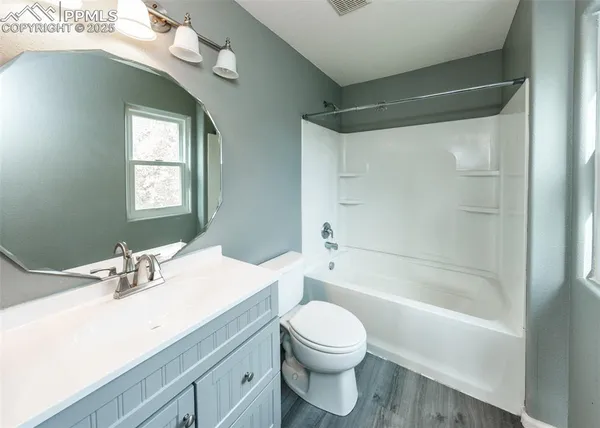 a bathroom with a bathtub shower sink vanity mirror and toilet