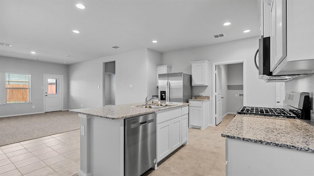 a kitchen with a sink stainless steel appliances a refrigerator and a stove top oven