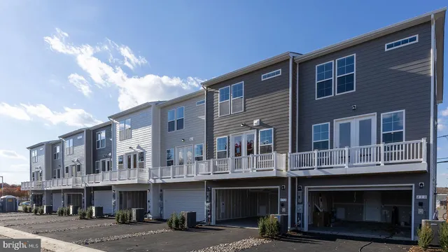 a front view of a building with lot of cars and trees