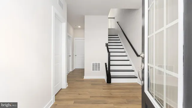 a view of a hallway with stairs and wooden floor