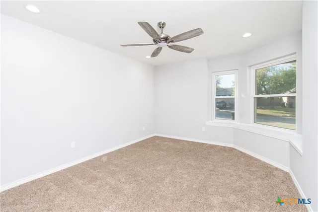 an empty room with window and ceiling fan