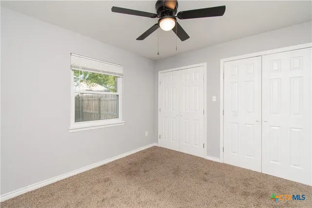 an empty room with fan and windows