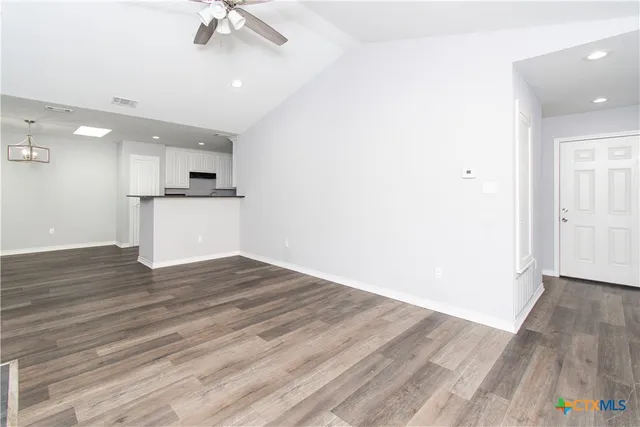 an empty room with wooden floor and a ceiling fan