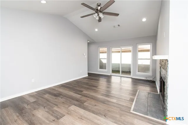 a view of an empty room with a window and wooden floor