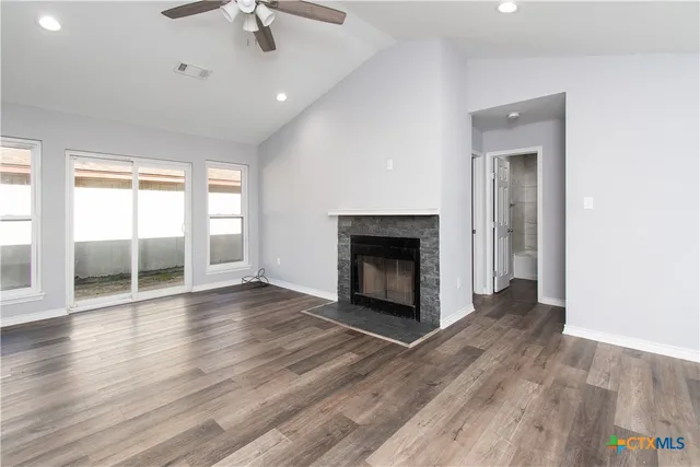 an empty room with wooden floor fireplace and windows