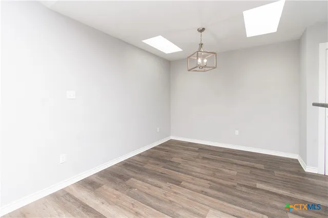 a view of a hallway with wooden floor and chandelier