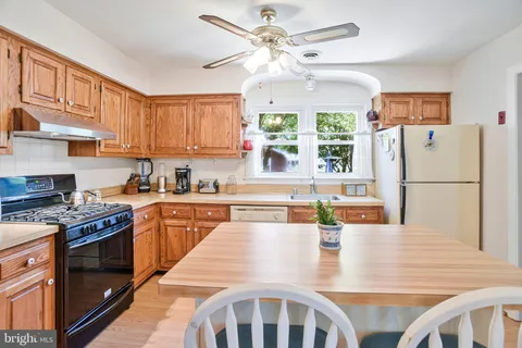a kitchen with stainless steel appliances granite countertop a refrigerator a stove a sink a dining table and chairs with wooden floor