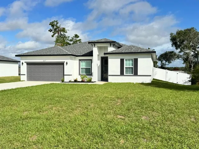 a front view of a house with a garden and trees