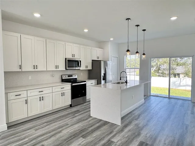 a large kitchen with stainless steel appliances granite countertop a stove a sink dishwasher a microwave oven and a wooden cabinets