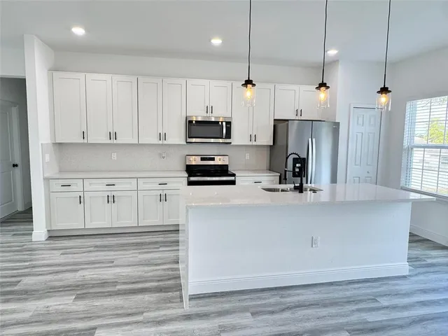 a kitchen with stainless steel appliances a refrigerator sink and white cabinets