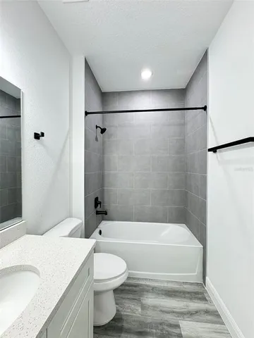 a bathroom with a granite countertop bathtub shower sink vanity and toilet
