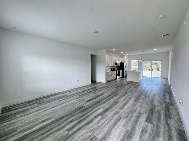 a view of a room with a wooden floor and a kitchen