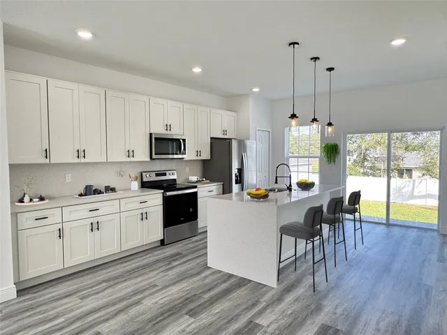 a kitchen with stainless steel appliances granite countertop a stove top oven a sink dishwasher a dining table and chairs with wooden floor