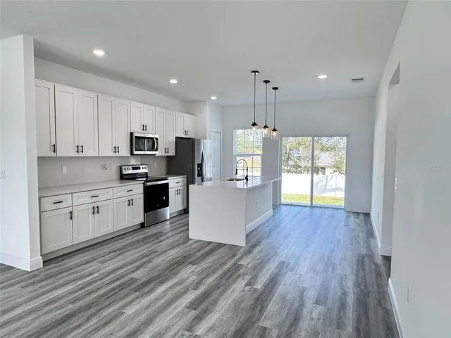 a large kitchen with cabinets wooden floor and stainless steel appliances