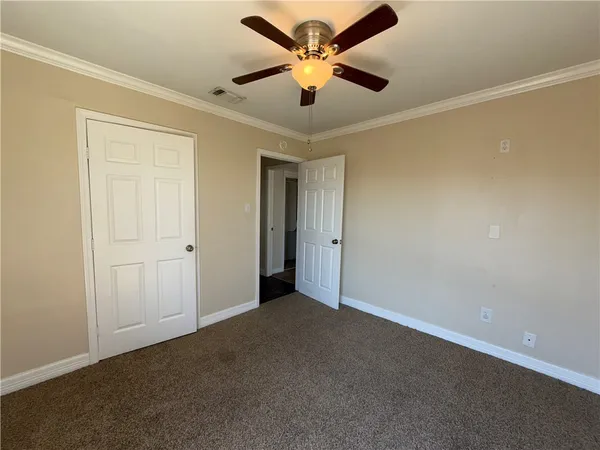 an empty room with wooden floor chandelier and windows