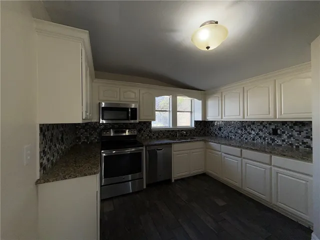an empty room with chandelier fan and windows