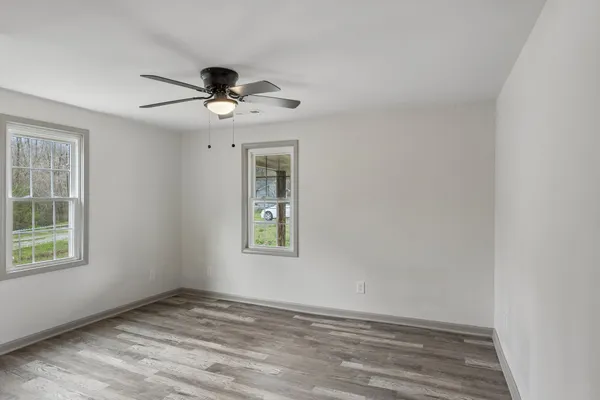 an empty room with windows and fan