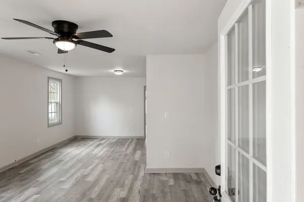 a view of empty room with wooden floor and fan
