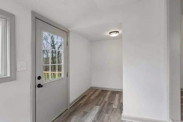 a view of an empty room with wooden floor and a window
