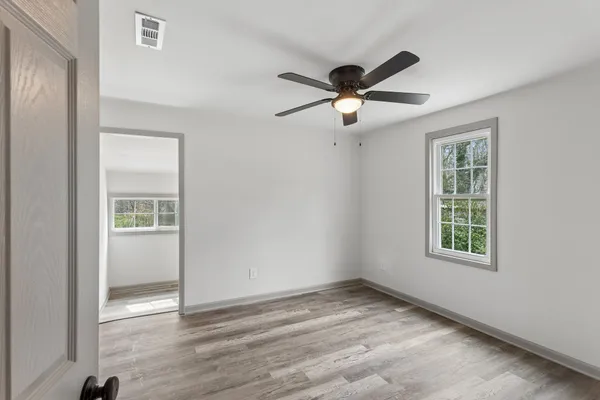 a view of empty room with wooden floor and fan