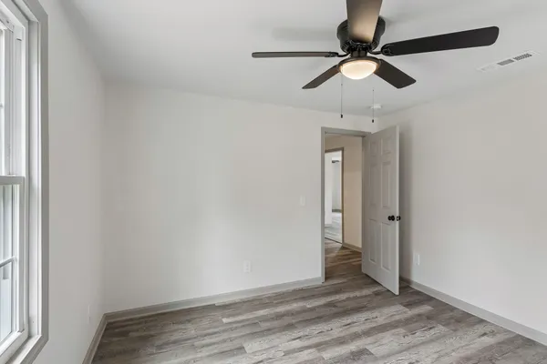 a view of an empty room with wooden floor and a window