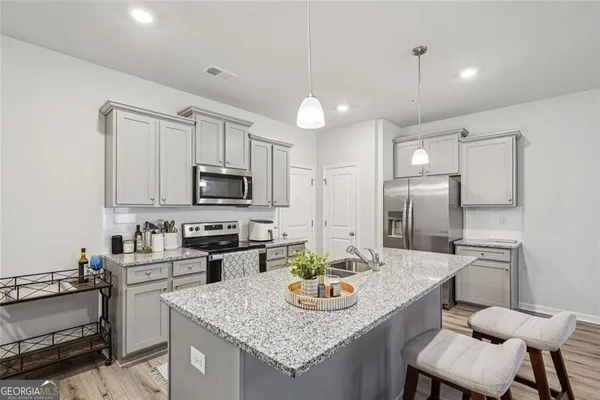 a kitchen with stainless steel appliances granite countertop a sink a stove a refrigerator cabinets and chairs