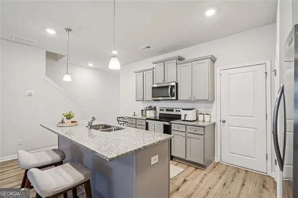 a kitchen with stainless steel appliances a sink a stove a refrigerator cabinets and living room view