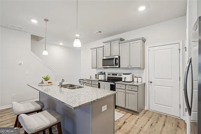 a kitchen with stainless steel appliances a sink a stove a refrigerator cabinets and living room view