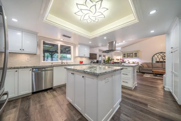 a kitchen with granite countertop white cabinets and stainless steel appliances