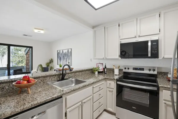 a kitchen with sink a microwave a stove and cabinets