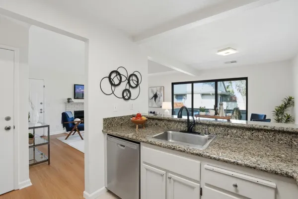 a kitchen with granite countertop a sink and dishwasher with wooden floor