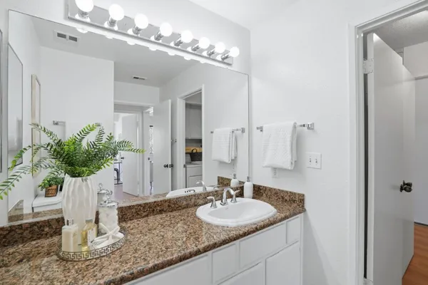 a bathroom with a granite countertop sink a toilet a large mirror and shower