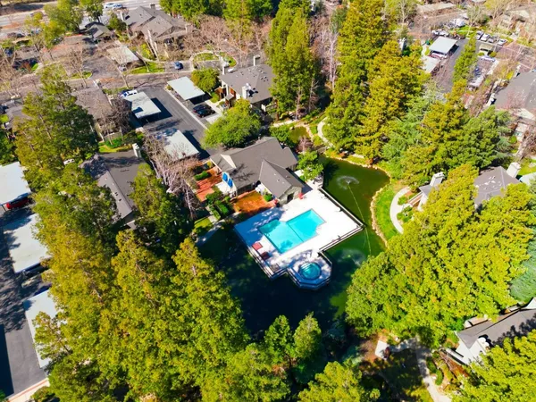 an aerial view of residential houses with outdoor space and trees all around