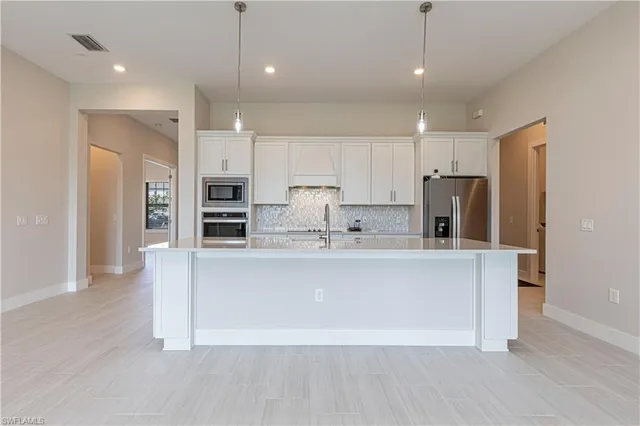 a view of kitchen with stainless steel appliances granite countertop a refrigerator a sink a stove and a wooden floors