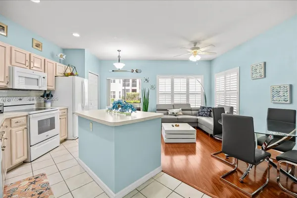a kitchen with stainless steel appliances kitchen island granite countertop a refrigerator a stove a sink dishwasher and white cabinets with wooden floor