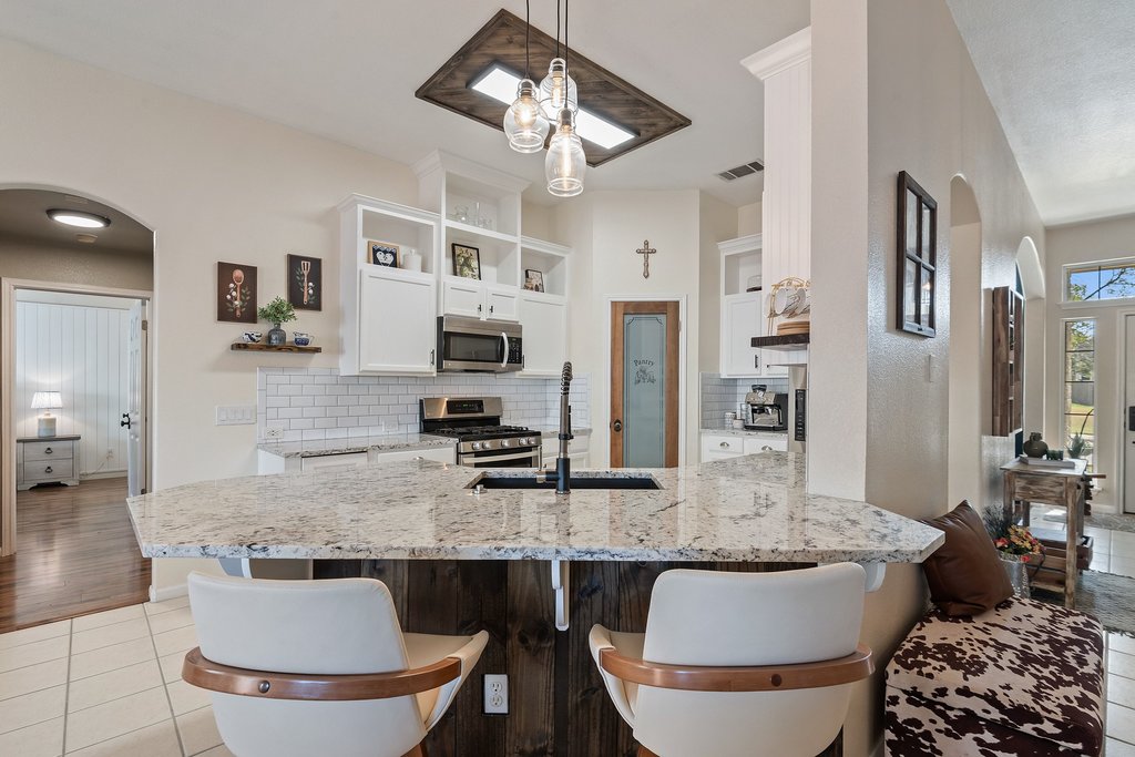 2305 Candle Ridge Trail Georgetown, TX 78626 - Photo 11 of 40 Kitchen featuring arched walkways, light tile patterned flooring, white cabinetry, and hanging light fixtures