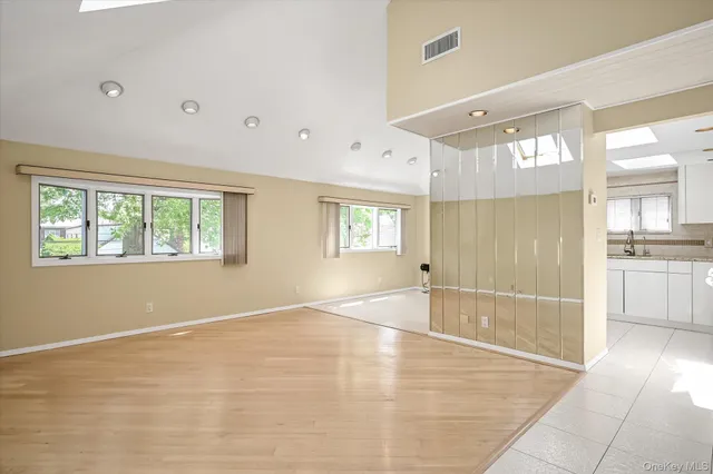a view of an empty room with window and wooden floor