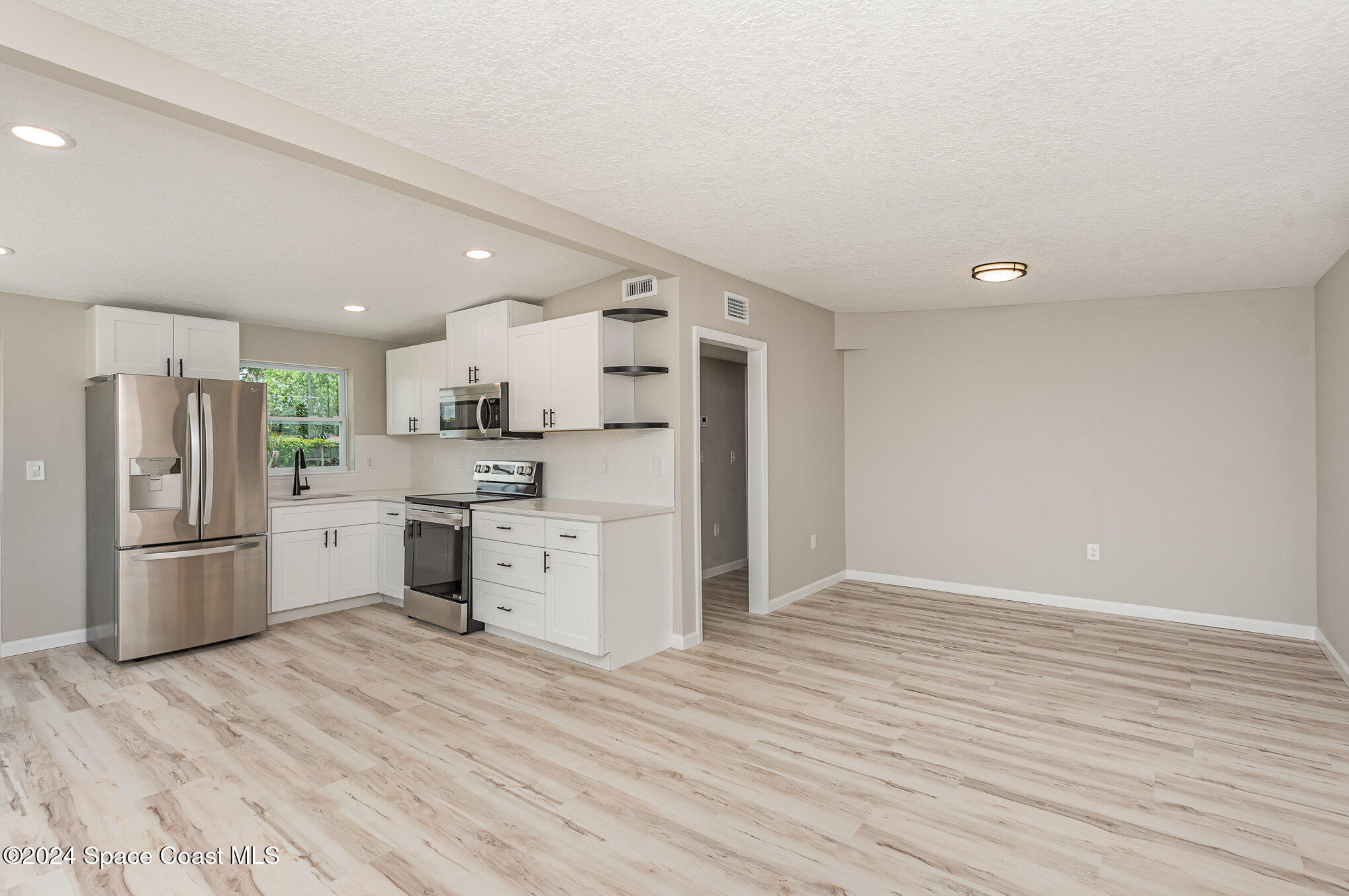 2626 Sarno Road Melbourne, FL 32935 - Photo 12 of 24 a kitchen with white cabinets and stainless steel appliances