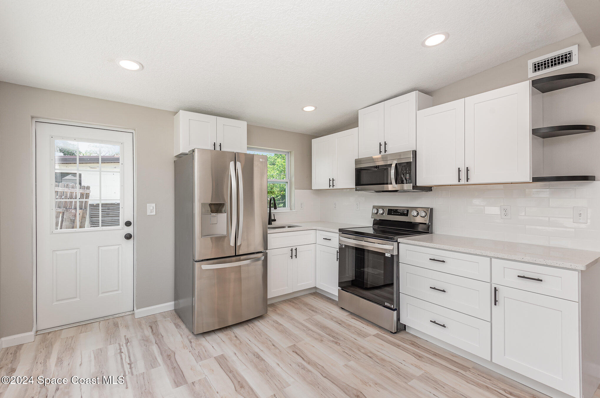 2626 Sarno Road Melbourne, FL 32935 - Photo 3 of 24 a kitchen with white cabinets stainless steel appliances and a refrigerator