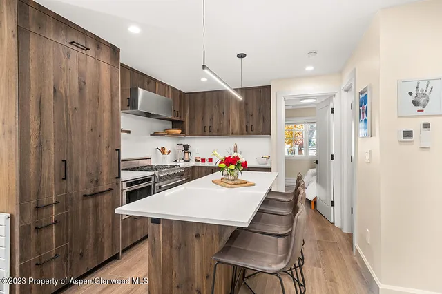 a kitchen with stainless steel appliances a sink a stove a refrigerator cabinets and wooden floor