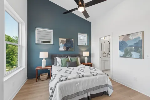 a bedroom with a bed painting on wall and a large window