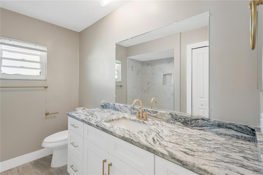 9840 San Sebastian Way Port Richey, FL 34668 - Photo 22 of 45 a bathroom with a granite countertop sink a toilet and a mirror
