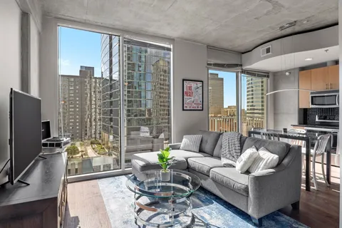 a living room with furniture a flat screen tv and a large window