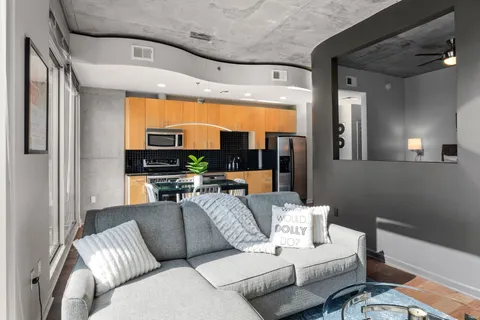 a living room with furniture kitchen view and a large window