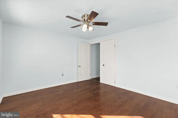 a view of empty room with wooden floor and ceiling fan